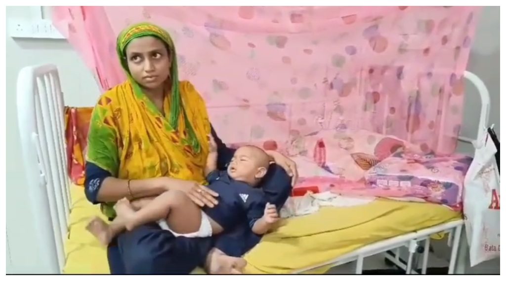 डेंगू पीड़ित बच्चे को गोद में लेकर बैठी महिला।