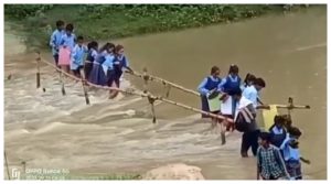 नदी पार करते स्कूली बच्चे।